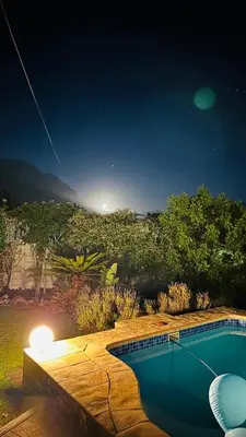 a swimming pool in a garden at night at Kleine Villa mit Pool und freie Sicht auf die Berge in Somerset West