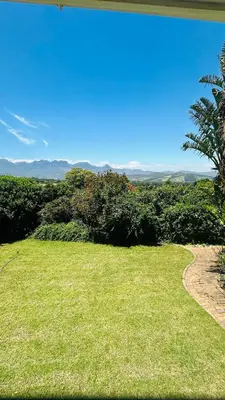 a grassy field with a road in the distance at Kleine Villa mit Pool und freie Sicht auf die Berge in Somerset West