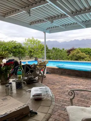 a patio with a table and a swimming pool at Kleine Villa mit Pool und freie Sicht auf die Berge in Somerset West