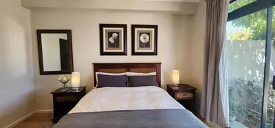 a bedroom with a bed and two night stands with lamps at Water side Town house on the canal in Cape Town