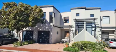 a white house with a staircase in front of it at Water side Town house on the canal in Cape Town