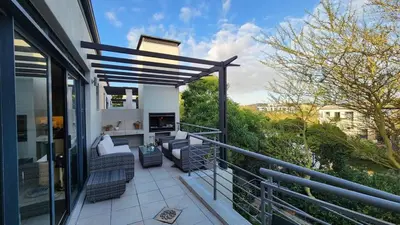 a balcony with chairs and a fireplace on a house at Water side Town house on the canal in Cape Town