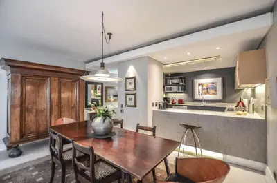 a kitchen and dining room with a wooden table and chairs at Stylish Apartment with Ocean Views - Dolphin Beach in Cape Town