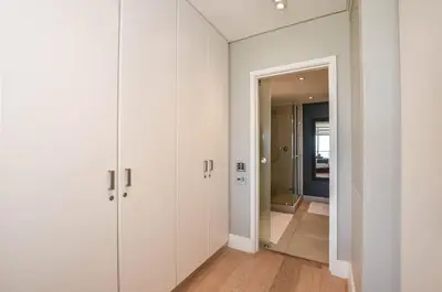 a hallway with white wardrobes and a mirror at Stylish Apartment with Ocean Views - Dolphin Beach in Cape Town