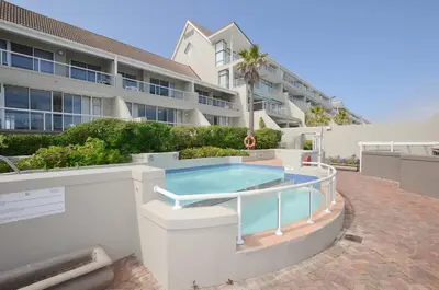 a swimming pool in front of a building at Stylish Apartment with Ocean Views - Dolphin Beach in Cape Town