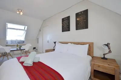 a bedroom with a large white bed and a table at Studio Apartment - Dolphin Beach in Cape Town