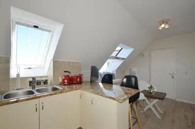 a kitchen with a sink and a counter with chairs at Studio Apartment - Dolphin Beach in Cape Town