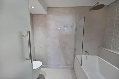 a bathroom with a shower and a tub and a toilet at 3 Bedroom Cabana on the Beach in Cape Town