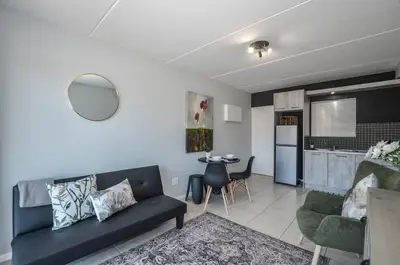 a living room with a blue couch and a kitchen at Modern 1 Bedroom Apartment in Blouberg in Cape Town
