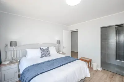 a white bedroom with a large bed and a shower at 3 Bedroom Apartment - Stunning Ocean Views in Cape Town