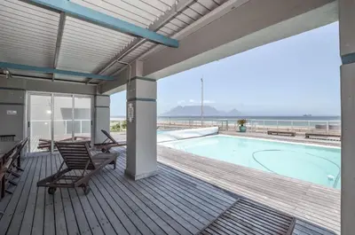 a deck with a swimming pool and chairs on a house at 3 Bedroom Apartment - Stunning Ocean Views in Cape Town