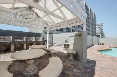 a patio with a table and chairs and a pool at 2 Bedroom Apartment - Zeezicht Blouberg in Cape Town