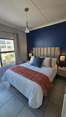 a bedroom with a large bed with a blue wall at Luxury Apartment in Somerset West in Strand