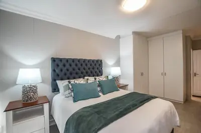 a bedroom with a large bed and two lamps at Modern 2 Bedroom Apartment At Dolphin Beach in Cape Town