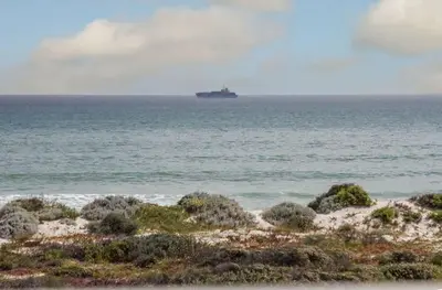 a ship in the ocean with a beach at Modern 2 Bedroom Apartment At Dolphin Beach in Cape Town
