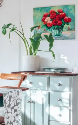 a glass cabinet with a vase of red flowers on it at Amulet At The Sea in Hermanus