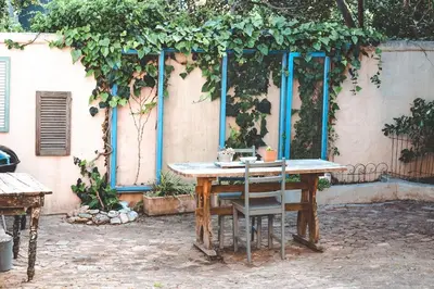 a wooden table with two chairs in front of a building at Amulet At The Sea in Hermanus