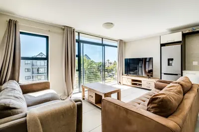 a living room with two couches and a tv at Canalside Tranquility in Cape Town