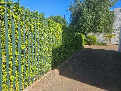 a green fence with yellow flowers on it at PinotageLuxuryCollection 14 Bastmolen in Stellenbosch