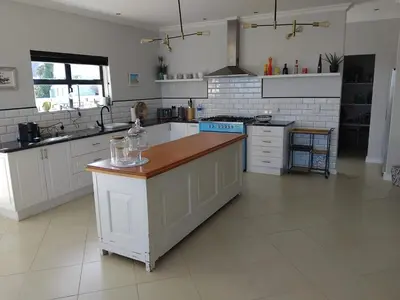 a large kitchen with white cabinets and a counter top at Chanteclair Holiday Home in Hermanus