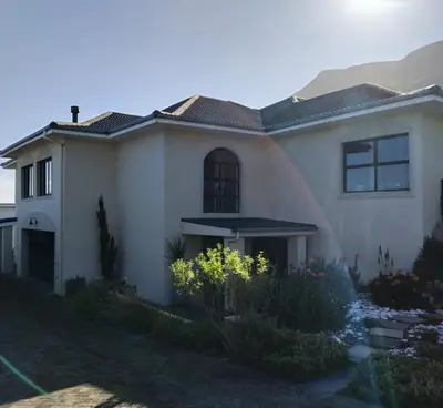 a white house with mountains in the background at Chanteclair Holiday Home in Hermanus
