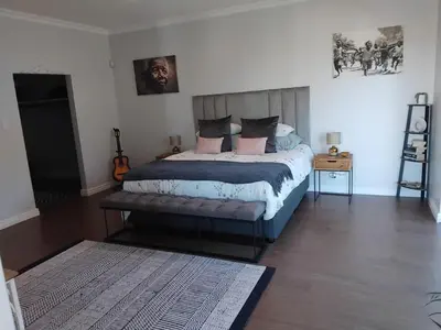 a bedroom with a bed with pink and blue pillows at Chanteclair Holiday Home in Hermanus