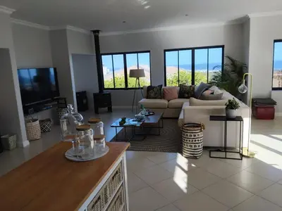 a living room with a couch and a tv at Chanteclair Holiday Home in Hermanus