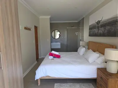 a bedroom with a bed with a pink bag on it at Dolphin Paradise in Cape Town
