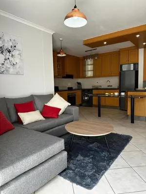 a living room with a couch and a table and a kitchen at Seaside Serenity in Cape Town