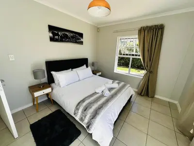 a bedroom with a large white bed and a window at Seaside Serenity in Cape Town
