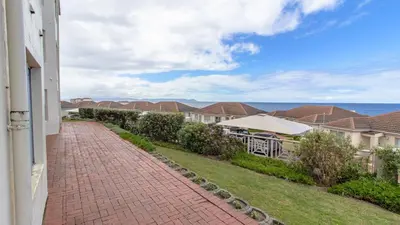 a brick walkway next to a house with the ocean at 258 Hermanus Beach club in Hermanus