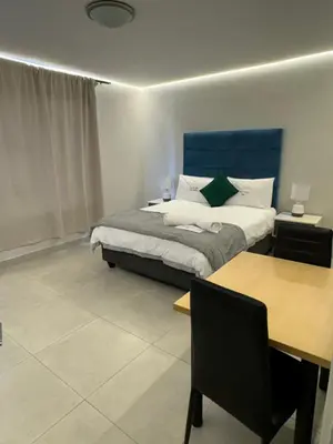 a bedroom with a bed with a blue headboard and a table at Ocean Whisper Room 6 minutes away from the beach in Cape Town