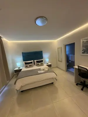 a bedroom with a large bed and a desk at Ocean Whisper Room 6 minutes away from the beach in Cape Town