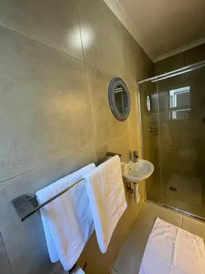a bathroom with a shower and a sink and towels at Ocean Whisper Room 6 minutes away from the beach in Cape Town
