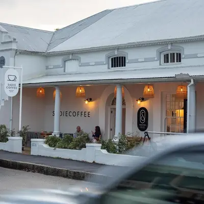 a woman sitting outside of a store at Dorpshuis Apartment, Main Street, Paarl in Paarl