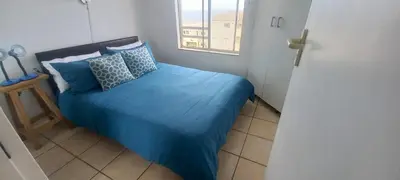 a small bedroom with a blue bed with a window at Unit 169 Hermanus Beach Club in Hermanus