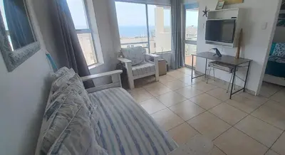 a bedroom with a bed and a tv and a balcony at Unit 169 Hermanus Beach Club in Hermanus