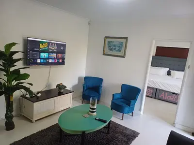 a living room with two chairs and a table and a tv at Greens Golf Course Apartment in De Grendel