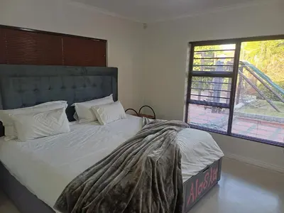 a large bed in a bedroom with two windows at Greens Golf Course Apartment in De Grendel