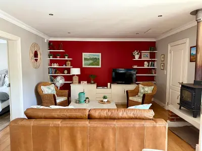 a living room with a couch and a red wall at Sipres Garden in Durbanville