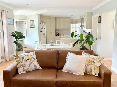 a living room with a brown couch and a kitchen at Sipres Garden in Durbanville