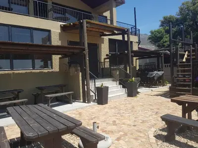 a picnic table and benches in front of a building at 4th On Boundary in Gordonʼs Bay