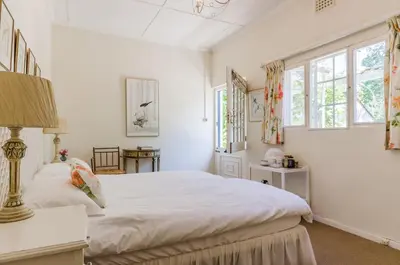 a white bedroom with a large bed and windows at Natte Valleij in Klapmuts