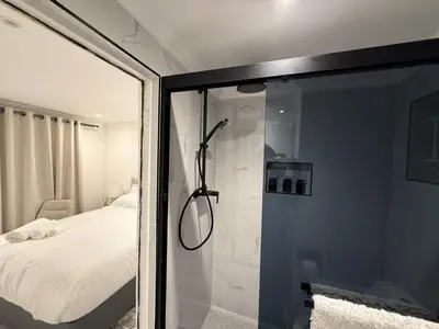 a bathroom with a glass shower with a bed at Cherrywood Guest House in Cape Town