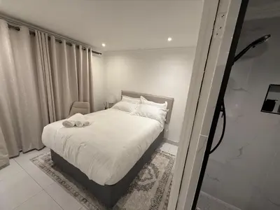 a bedroom with a bed with white sheets and white pillows at Cherrywood Guest House in Cape Town