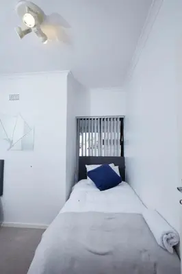 a bedroom with a bed with a blue pillow at Townhouse in Bloubergstrand in Cape Town
