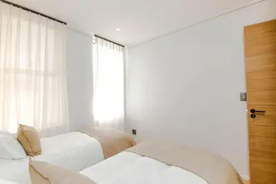 two beds in a bedroom with white walls and a window at Stylish Apartment in Cape Winelands District in Stellenbosch