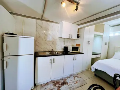 a kitchen with a sink and a refrigerator and a bed at White Pearl at Strand in Strand