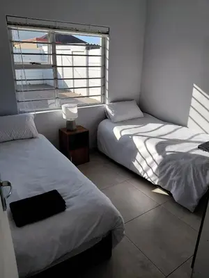 two beds in a room with a window at Rihla Residences - Hanbury Road in Cape Town