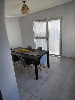 a dining room with a black table and chairs at Rihla Residences - Hanbury Road in Cape Town